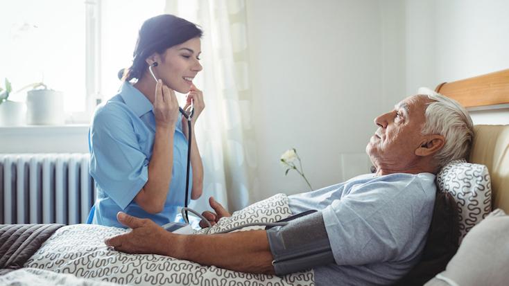 nurse speaking to a resident who is in a bed